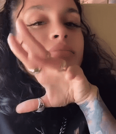 A Close Up Of A Woman 'S Face With Her Hand On Her Face . She Is Wearing A Ring On Her Finger . GIF