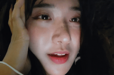 A Close Up Of A Woman 'S Face With Her Hand On Her Forehead GIF