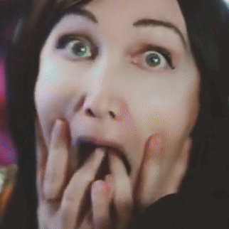 A Close Up Of A Woman 'S Face With Her Hand On Her Mouth GIF