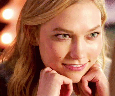 A Close Up Of A Woman 'S Face With Her Hands On Her Face And Smiling . GIF
