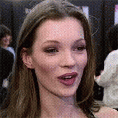 A Close Up Of A Woman 'S Face With Her Mouth Open And A Crowd Behind Her . GIF
