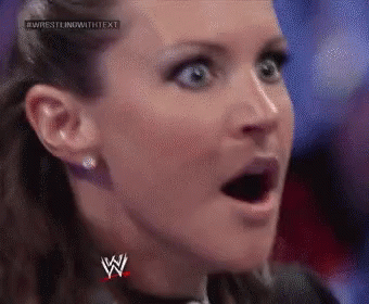 A Close Up Of A Woman 'S Face With Her Mouth Open And A Wrestling Logo On Her Chest . GIF
