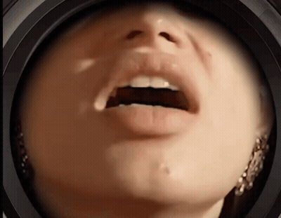 A Close Up Of A Woman 'S Face With Her Mouth Open And Earrings GIF