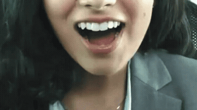 A Close Up Of A Woman 'S Face With Her Mouth Open And Her Teeth Showing . GIF