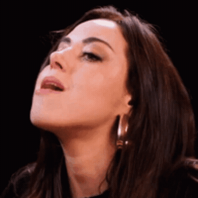 A Close Up Of A Woman 'S Face With Her Mouth Open And Her Tongue Out . GIF