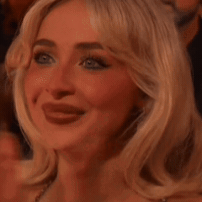 A Close Up Of A Woman 'S Face With Her Tongue Hanging Out While Applauding . GIF