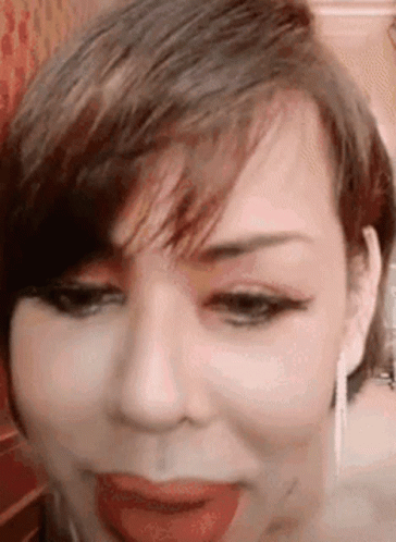 A Close Up Of A Woman 'S Face With Her Tongue Out GIF