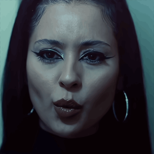 A Close Up Of A Woman 'S Face With Hoop Earrings On GIF