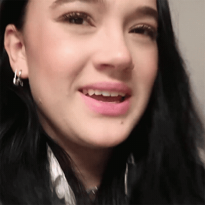 A Close Up Of A Woman 'S Face With Hoop Earrings On GIF