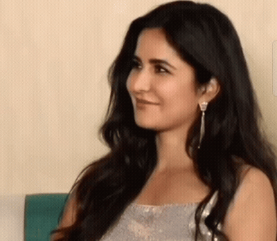 A Close Up Of A Woman 'S Face With Long Black Hair And Earrings . GIF
