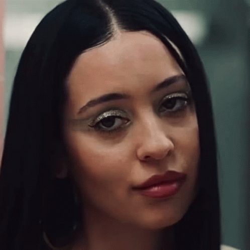 A Close Up Of A Woman 'S Face With Long Black Hair And Red Lipstick . GIF