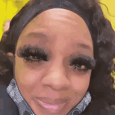 A Close Up Of A Woman 'S Face With Long Eyelashes And A Headband On . GIF
