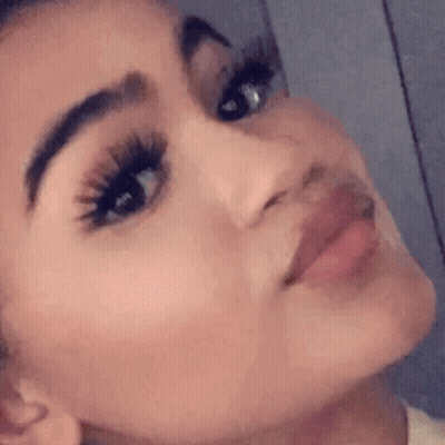 A Close Up Of A Woman 'S Face With Long Eyelashes And A Slight Smile . GIF