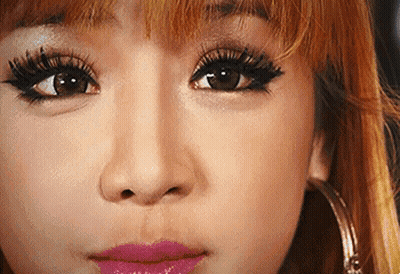 A Close Up Of A Woman 'S Face With Long Eyelashes , Pink Lips And Hoop Earrings . GIF