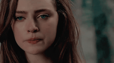 A Close Up Of A Woman 'S Face With Long Hair And Blue Eyes GIF