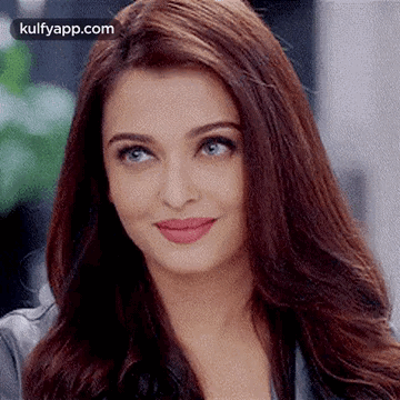 A Close Up Of A Woman 'S Face With Long Hair And Blue Eyes Smiling . GIF