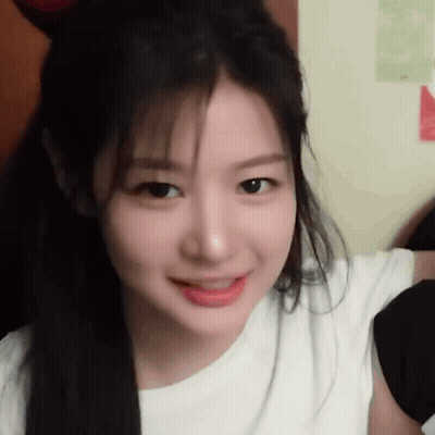 A Close Up Of A Woman 'S Face With Long Hair Wearing A White Shirt . GIF