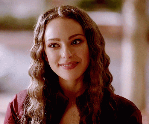 A Close Up Of A Woman 'S Face With Long Wavy Hair GIF