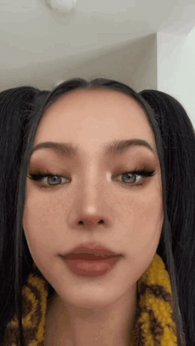 A Close Up Of A Woman 'S Face With Pigtails And Red Lips . GIF