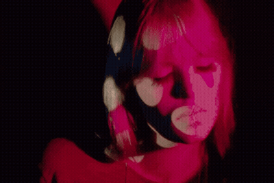 A Close Up Of A Woman 'S Face With Pink Flowers Projected On Her Face GIF