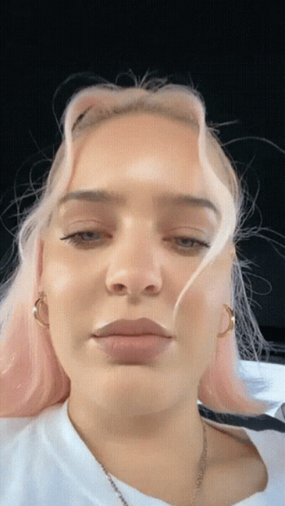A Close Up Of A Woman 'S Face With Pink Hair And A White Shirt GIF