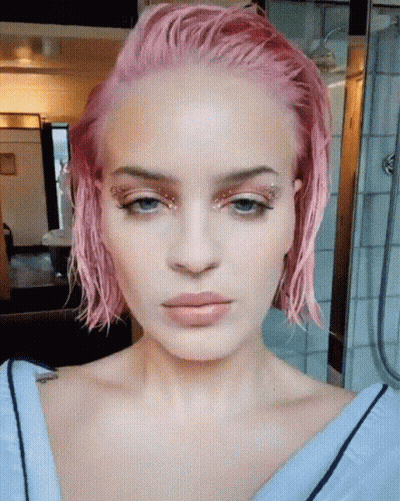 A Close Up Of A Woman 'S Face With Pink Hair And Blue Eyes GIF