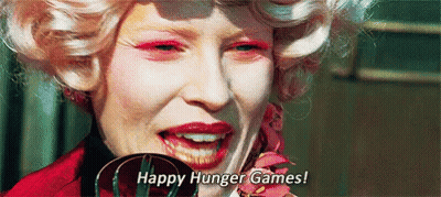 A Close Up Of A Woman 'S Face With Pink Makeup And The Words `` Happy Hunger Games ! '' GIF