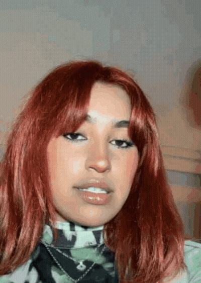 A Close Up Of A Woman 'S Face With Red Hair And A Camouflage Shirt . GIF