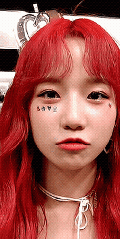 A Close Up Of A Woman 'S Face With Red Hair And A Choker GIF