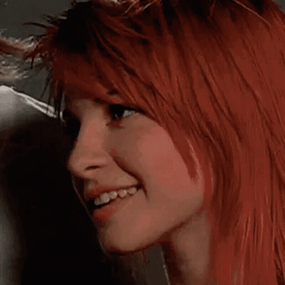 A Close Up Of A Woman 'S Face With Red Hair And A Smile . GIF