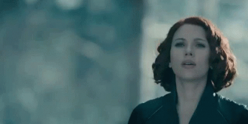 A Close Up Of A Woman 'S Face With Red Hair In A Black Jacket . GIF