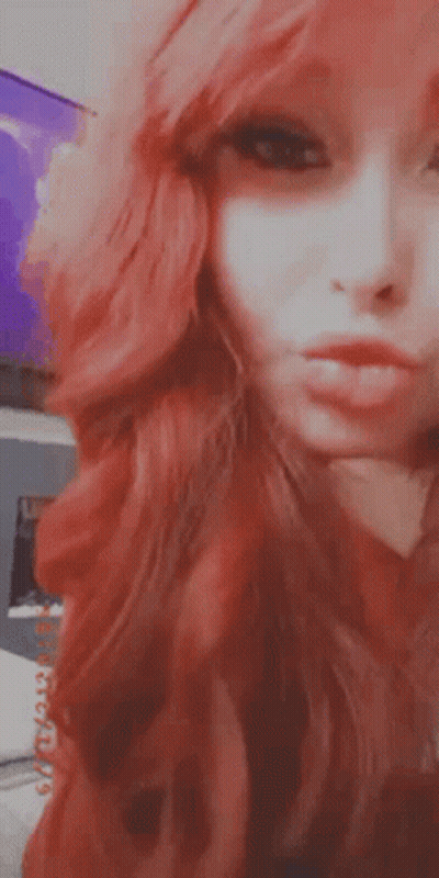 A Close Up Of A Woman 'S Face With Red Hair Making A Funny Face . GIF