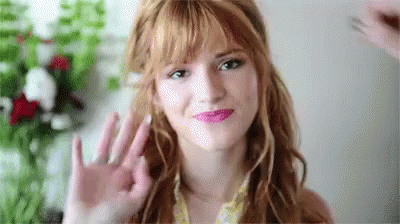 A Close Up Of A Woman 'S Face With Red Hair Waving Her Hand . GIF