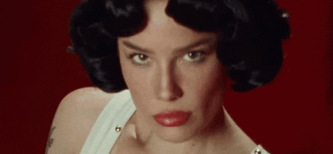 A Close Up Of A Woman 'S Face With Red Lips And Black Hair On A Red Background . GIF