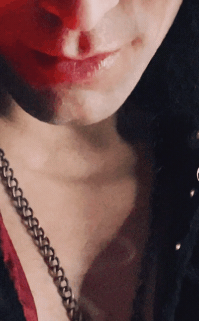 A Close Up Of A Woman 'S Face With Red Lipstick And A Chain Around Her Neck GIF