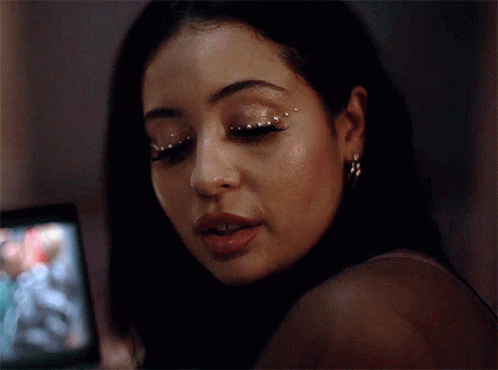 A Close Up Of A Woman 'S Face With Rhinestones On Her Eyes And Earrings . GIF