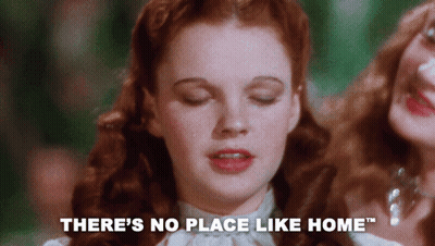A Close Up Of A Woman 'S Face With The Words " There 'S No Place Like Home " Behind Her GIF