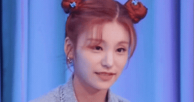 A Close Up Of A Woman 'S Face With Two Buns In Her Hair . GIF