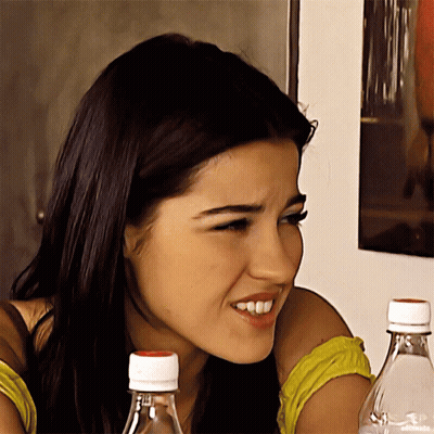 A Close Up Of A Woman 'S Face With Two Water Bottles In The Background GIF