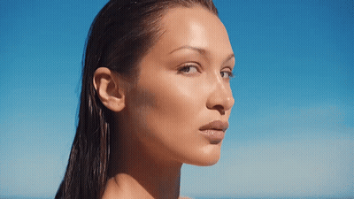 A Close Up Of A Woman 'S Face With Wet Hair Against A Blue Sky GIF