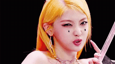 A Close Up Of A Woman 'S Face With Yellow Hair Holding A Sword . GIF