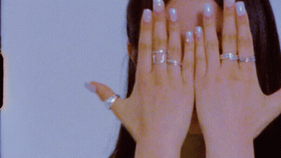 A Close Up Of A Woman 'S Hand With Rings On It Covering Her Face . GIF