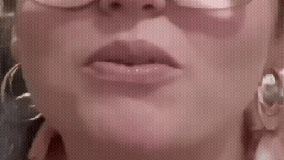 A Close Up Of A Woman 'S Lips With Glasses And Hoop Earrings . GIF