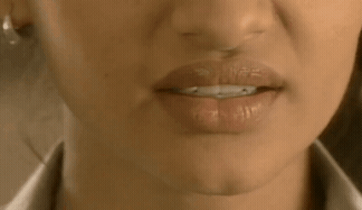 A Close Up Of A Woman 'S Mouth With Her Tongue Out And A White Shirt On . GIF