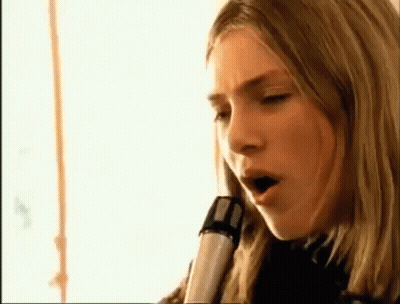 A Close Up Of A Woman Singing Into A Microphone GIF