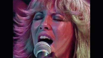 A Close Up Of A Woman Singing Into A Microphone GIF
