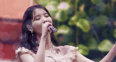 A Close Up Of A Woman Singing Into A Microphone On A Stage . GIF