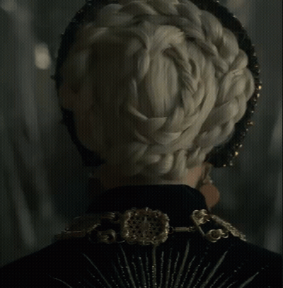 A Close Up Of A Woman Wearing A Black And Gold Outfit GIF