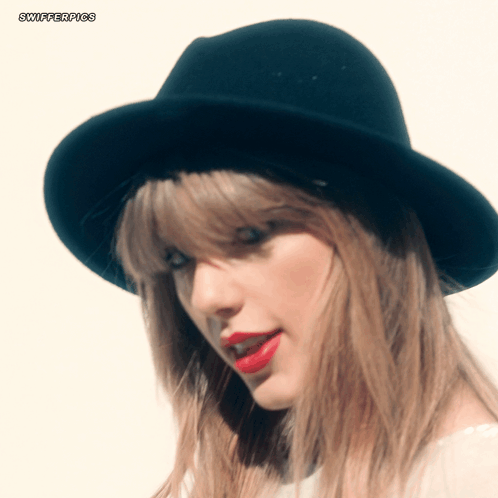 A Close Up Of A Woman Wearing A Black Hat With Swifterpics Written On The Bottom Left GIF