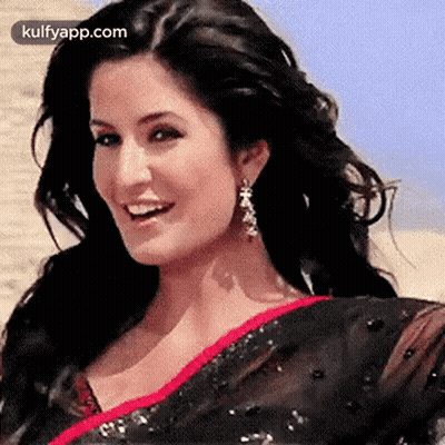 A Close Up Of A Woman Wearing A Black Saree And Earrings Smiling . GIF
